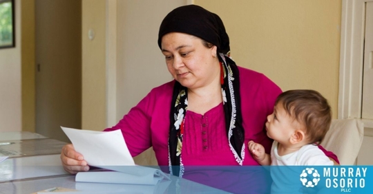 Foreign mother looking at a paper with her toddler son in her lap